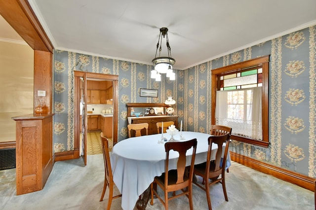 dining room with baseboards, ornamental molding, and light colored carpet