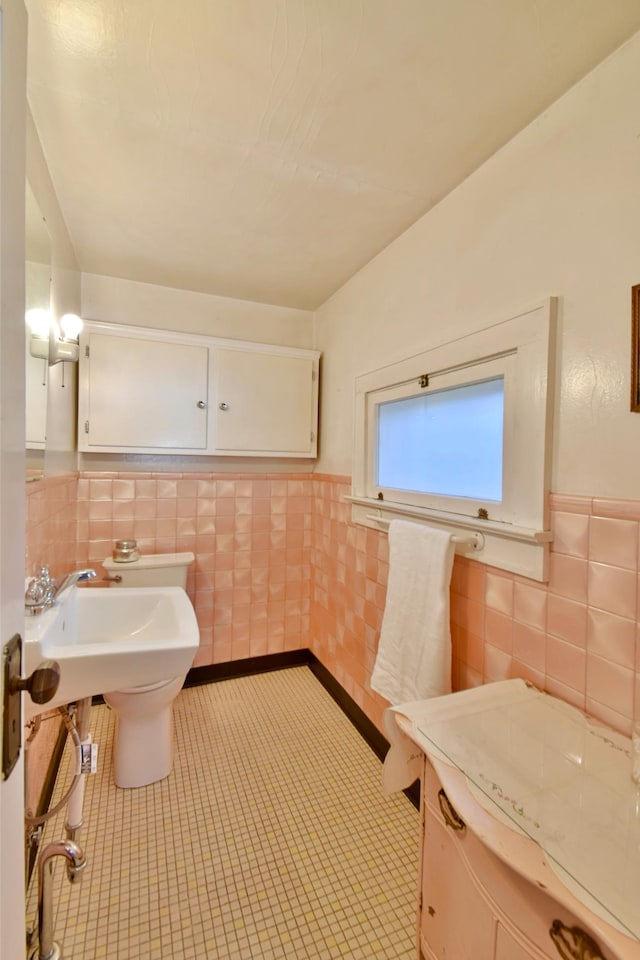 half bath with tile walls, a wainscoted wall, and tile patterned floors
