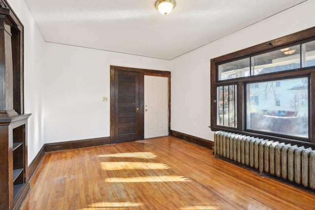 spare room featuring hardwood / wood-style floors, radiator heating unit, and a textured ceiling