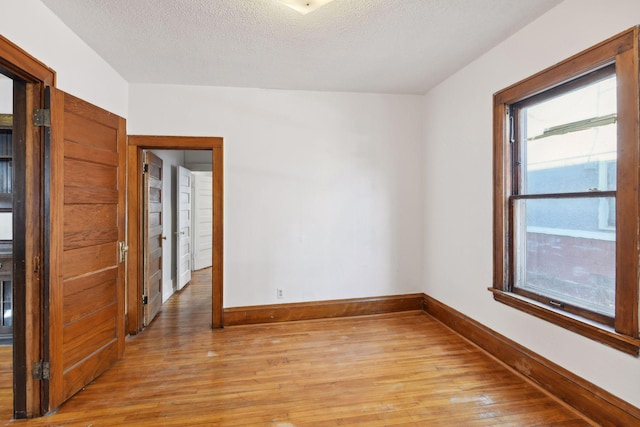 unfurnished room featuring a textured ceiling and light hardwood / wood-style flooring