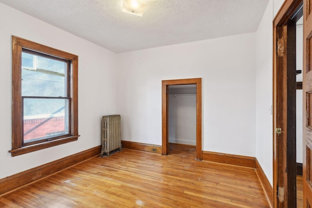 unfurnished bedroom featuring radiator, a closet, light hardwood / wood-style floors, and a textured ceiling