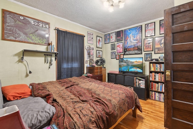 bedroom featuring light hardwood / wood-style flooring, a textured ceiling, and ornamental molding