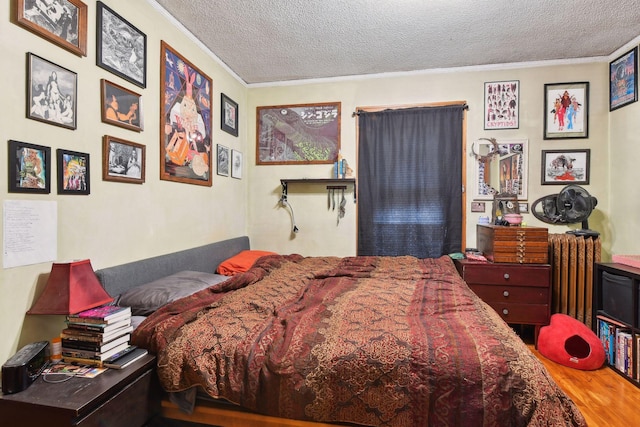 bedroom with hardwood / wood-style flooring, crown molding, a textured ceiling, and radiator