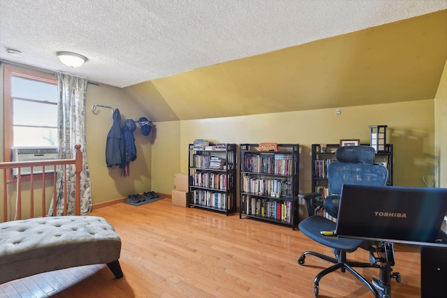 office with a textured ceiling, hardwood / wood-style floors, cooling unit, and lofted ceiling