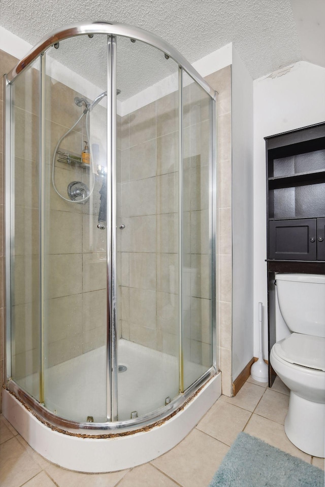 bathroom with tile patterned flooring, an enclosed shower, a textured ceiling, and toilet