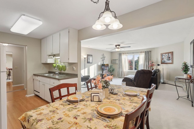 dining area featuring a wall mounted air conditioner, light hardwood / wood-style flooring, sink, and ceiling fan with notable chandelier