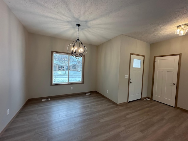 entrance foyer with a textured ceiling, a notable chandelier, and hardwood / wood-style flooring