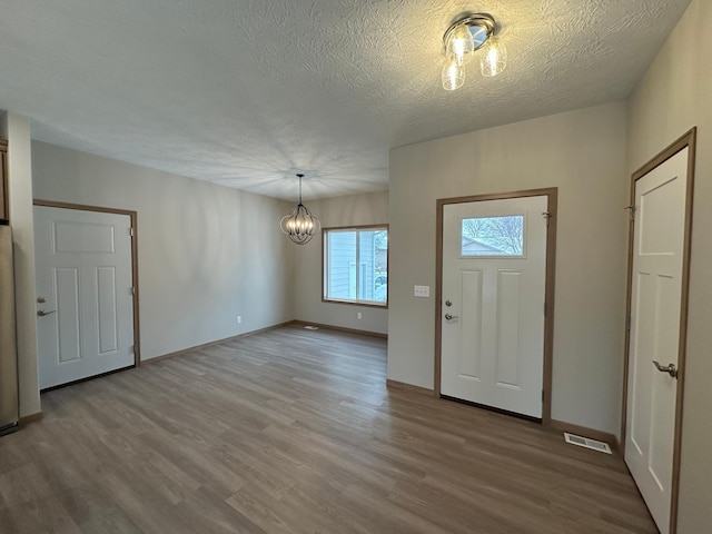 foyer featuring wood-type flooring, a textured ceiling, and an inviting chandelier