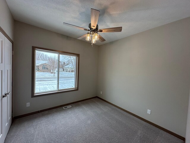 spare room with carpet, ceiling fan, and a textured ceiling