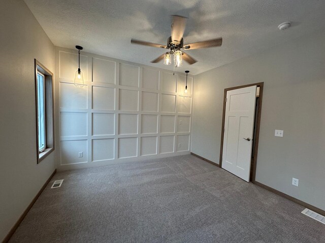 carpeted empty room featuring ceiling fan and a textured ceiling