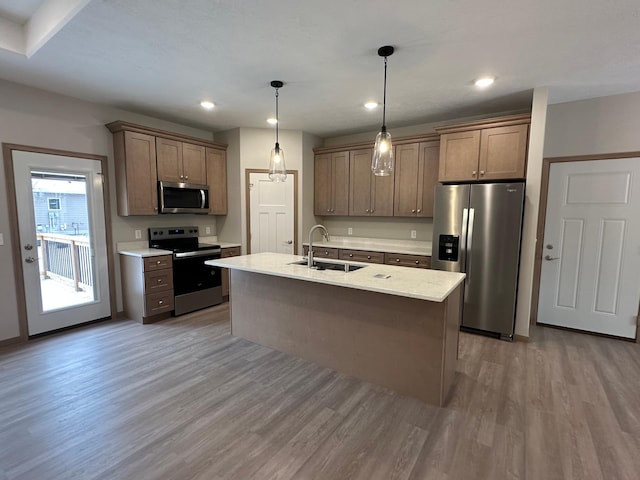 kitchen with hardwood / wood-style floors, pendant lighting, a center island with sink, sink, and appliances with stainless steel finishes