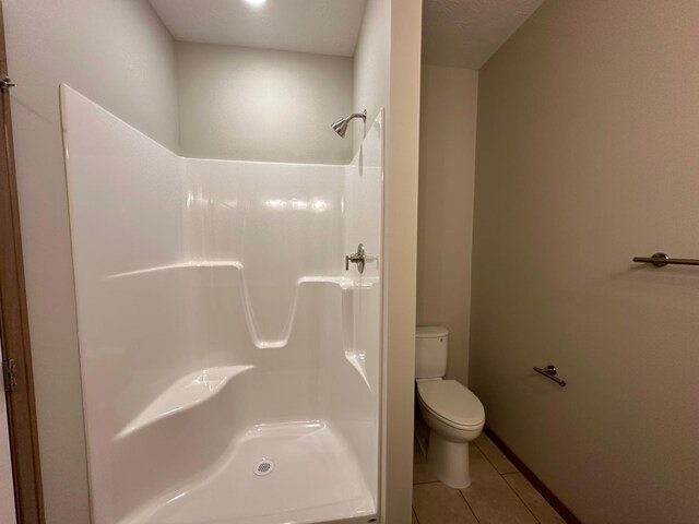 bathroom featuring tile patterned flooring, toilet, and walk in shower