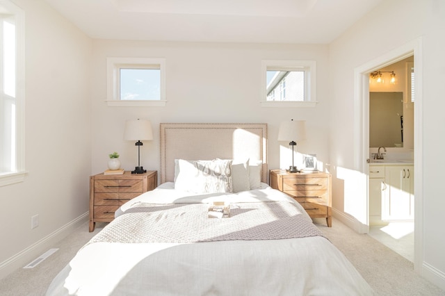 carpeted bedroom with ensuite bath and sink