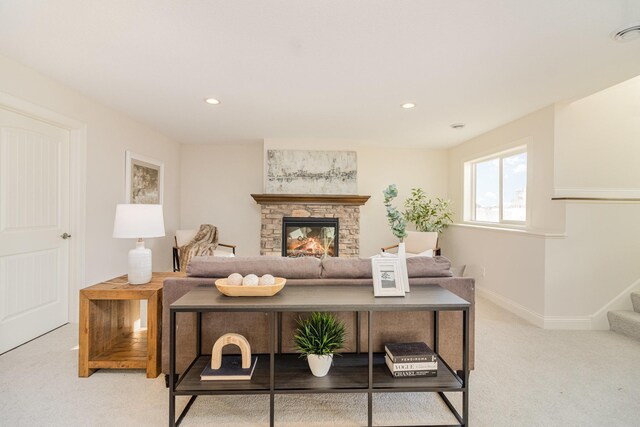 carpeted living room with a stone fireplace