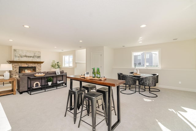 carpeted dining space featuring a stone fireplace