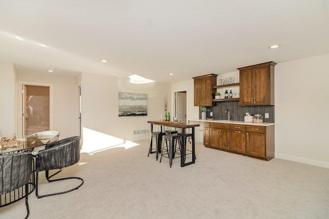 kitchen featuring sink, light colored carpet, and a kitchen breakfast bar