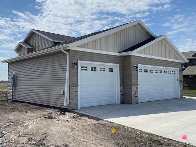 1312 Southview Dr SW, Glyndon, MN 56547 - view of side of home featuring an attached garage, driveway, board and batten siding, and stone siding