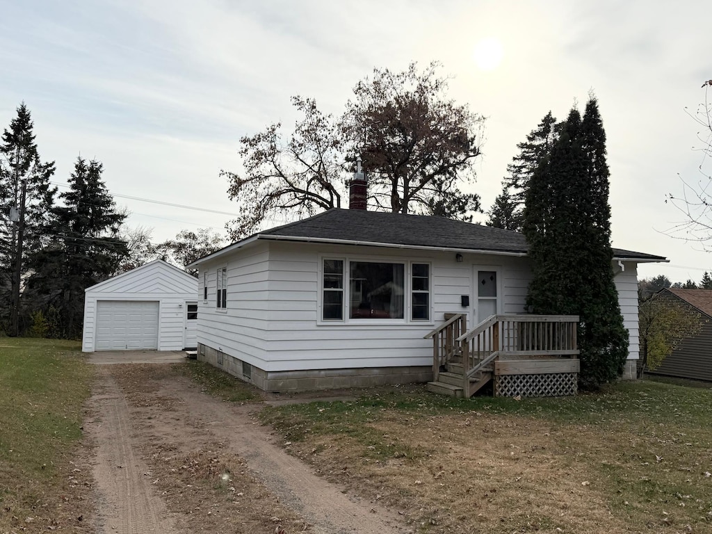 view of front of property featuring a front yard, an outdoor structure, and a garage