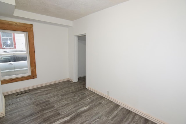 unfurnished room with dark hardwood / wood-style flooring and a textured ceiling