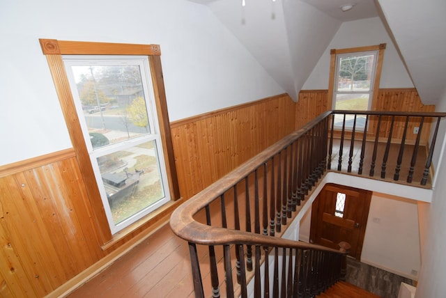 stairway with wood walls, hardwood / wood-style flooring, and lofted ceiling with skylight