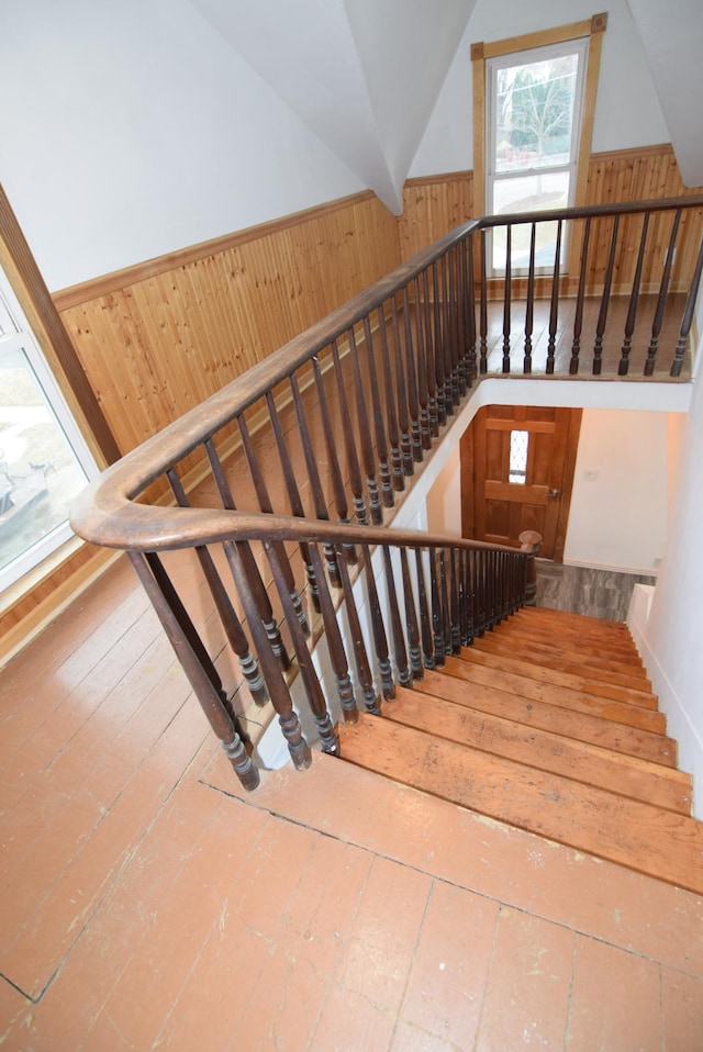 stairs featuring wooden walls, hardwood / wood-style floors, and vaulted ceiling