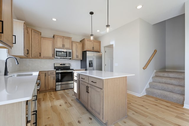 kitchen with decorative light fixtures, light hardwood / wood-style floors, appliances with stainless steel finishes, and a center island