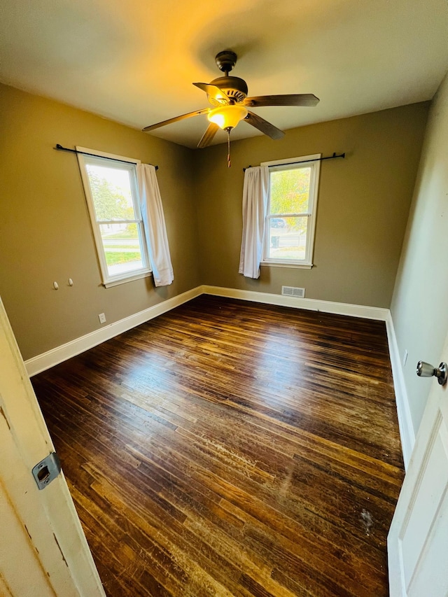 unfurnished room featuring ceiling fan, a healthy amount of sunlight, and dark hardwood / wood-style floors