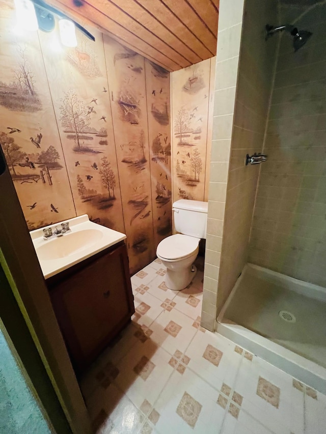 bathroom featuring toilet, vanity, and a tile shower