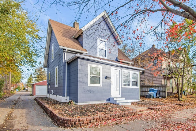 view of front of house with a garage and an outbuilding