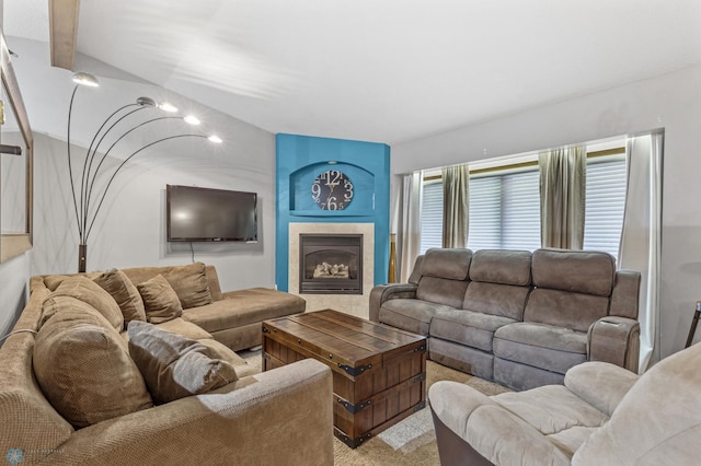 carpeted living room with a tiled fireplace and vaulted ceiling with beams