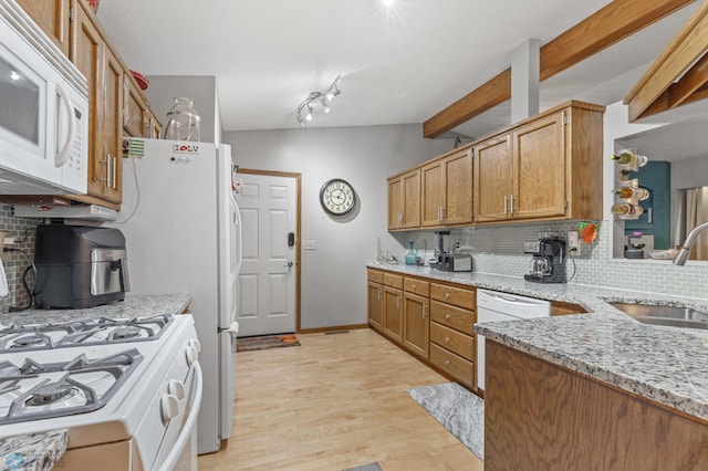 kitchen with sink, tasteful backsplash, white appliances, light wood-type flooring, and lofted ceiling with beams