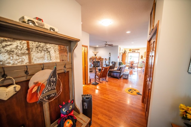 mudroom featuring ceiling fan, a stone fireplace, and hardwood / wood-style floors