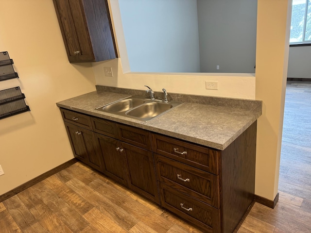 kitchen with sink, dark brown cabinets, and light wood-type flooring