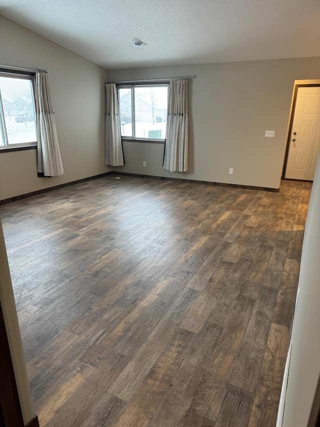 unfurnished room featuring a textured ceiling and dark hardwood / wood-style flooring