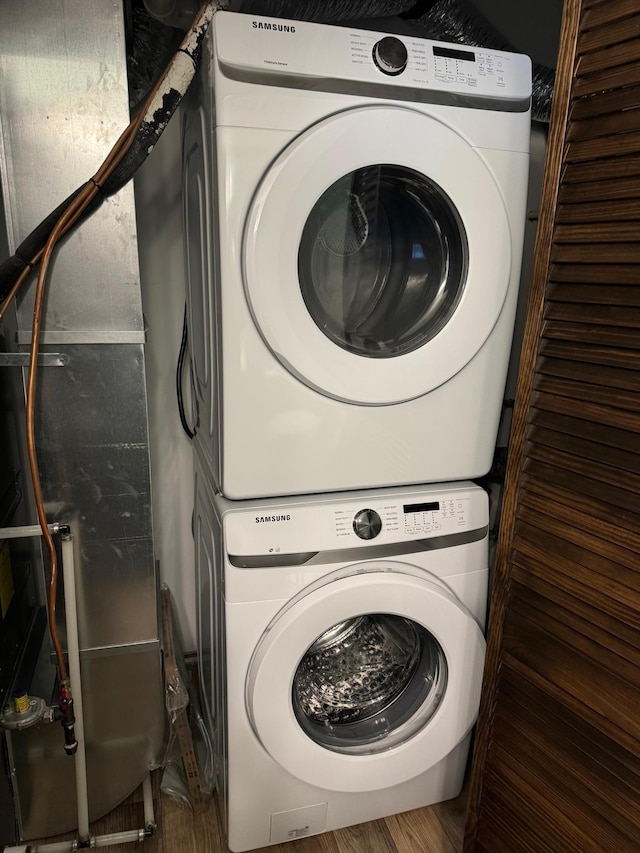 washroom with stacked washer and clothes dryer and wood-type flooring