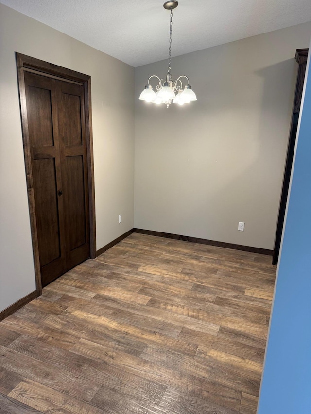 unfurnished dining area featuring a notable chandelier and dark hardwood / wood-style floors