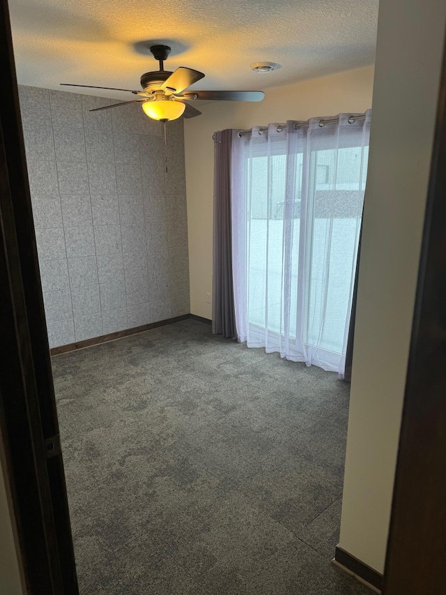 empty room with ceiling fan, carpet flooring, and a textured ceiling