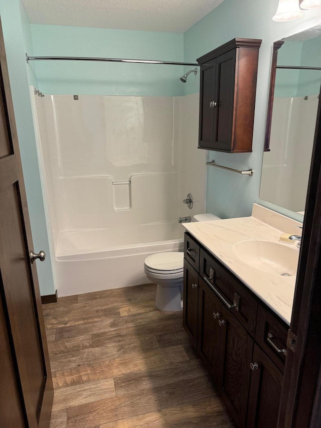 full bathroom featuring shower / tub combination, a textured ceiling, hardwood / wood-style flooring, toilet, and vanity