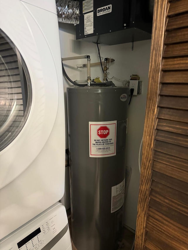 utility room with water heater and stacked washer / dryer