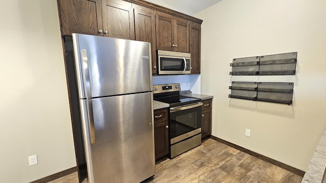 kitchen featuring light wood-type flooring, dark brown cabinetry, baseboards, and appliances with stainless steel finishes