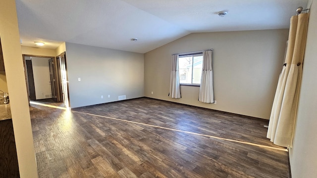 additional living space featuring vaulted ceiling, visible vents, dark wood finished floors, and baseboards