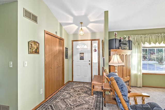 foyer entrance featuring carpet floors, a textured ceiling, and vaulted ceiling