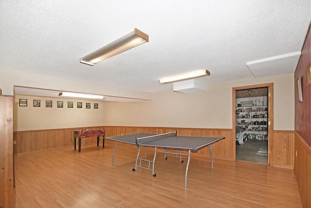 game room with a textured ceiling, wooden walls, and hardwood / wood-style flooring