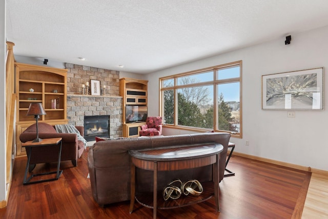 living room featuring dark wood-type flooring, a brick fireplace, and a textured ceiling