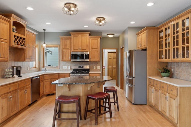 kitchen with sink, a breakfast bar area, appliances with stainless steel finishes, a center island, and decorative light fixtures