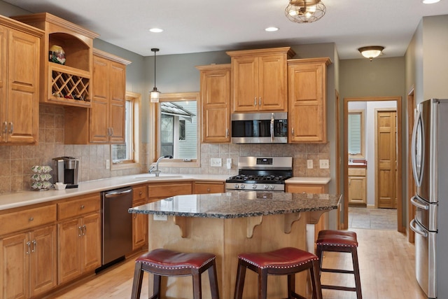 kitchen with a kitchen bar, sink, decorative light fixtures, a center island, and appliances with stainless steel finishes