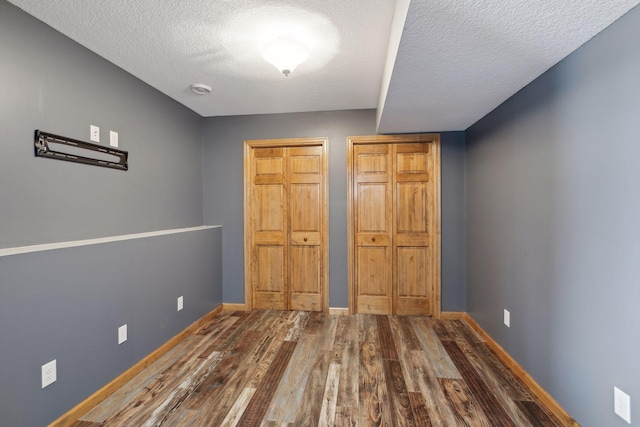 unfurnished bedroom with hardwood / wood-style floors, a textured ceiling, and multiple closets