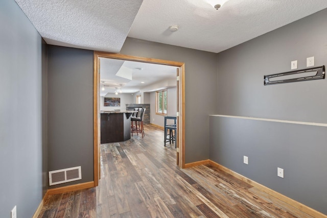 corridor with dark wood-type flooring and a textured ceiling