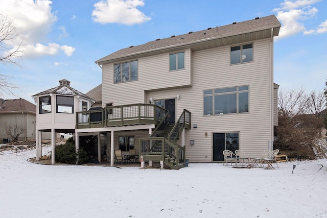 snow covered house with a wooden deck and a gazebo