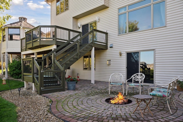 rear view of property featuring a patio, a deck, and an outdoor fire pit